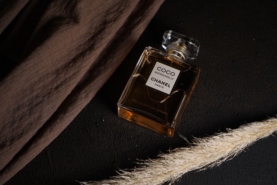 Close-up shot of Chanel Coco Mademoiselle perfume on a stylish black surface with dramatic lighting.