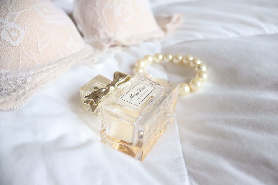 Chic perfume bottle beside lace lingerie and pearls, ideal for fashion and beauty themes.